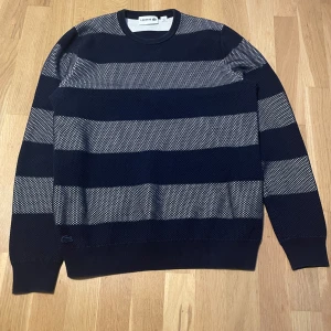 Lacoste sweatshirt - Assnygg randig lacoste sweatshirt med mesh-material. Är blå/vit, i superbra skick och kostar 1800 ny! Står 4/M men passar S. Säljer då den blivit för liten för mig.