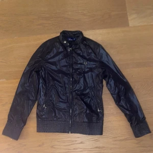 Fred Perry Windbreaker - Säljer en stilfull Fred Perry Windbreaker, i utmärkt skick. Dess glansiga yta ger en unik touch, och den är perfekt för någon som är 164 cm. Priset diskuteras. Har du frågor? Tveka inte med att ställa dem. Ett elegant tillskott till din garderob.