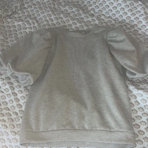 Kortärmad tjocktröja  - Kortärmad tjocktröja i beige färg och glittrig!, finaste tröjan jag har men kommer aldrig till användning! Nyskick aldrig använd(tror den inte går att köpa längre!)!!!Itressekoll!!