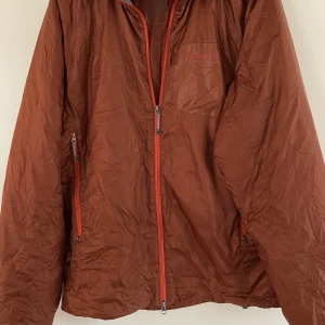 Houdini ”Dunfri”  - Toppenhärlig jacka, lätt vikt, kan användas istället för flis under vindjacka. Koppar/roströd med orange detaljer kring blixtlås.