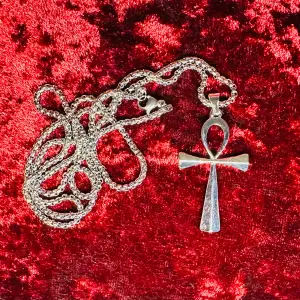 Nytt silverfärgat halsband i rostfritt stål med ankh-symbol.   Stilrent och kraftfullt.   Amuletten är 4,3 cm lång x 2,5 cm bred. 50 cm kedja.   Tåligt material.  Nytt och oanvänt.