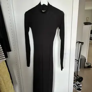 En lång lite tunnare svart klänning från Gina Tricot 🥰 storlek XS! Supersnygg öppen rygg med hål för tummarna i slutet på ärmarna 🩷 