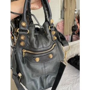 Balenciaga pompon väska - Intressekoll på min fina balenciaga väska köpt på vestaire collective för ca 1 år sen, gott skick. Har kvitto och äkthetsbevis. Den rymmer mycket och funkar jättebra som tex skolväska, måtten är ca 42x38 cm. Inga skambud, köp direkt för 6500!