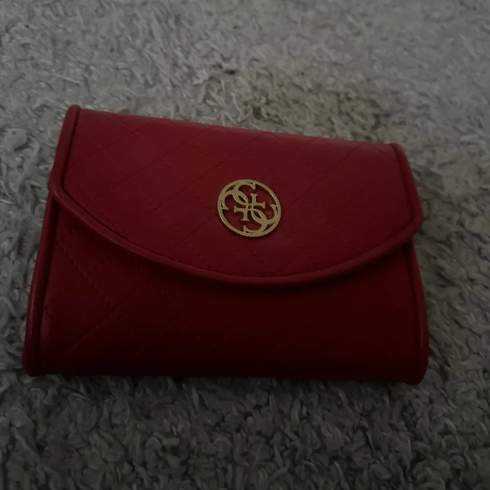 Röd plånbok från guess med band till så går att ha som väska, aldrig använt innan i fint skick . Väskor.