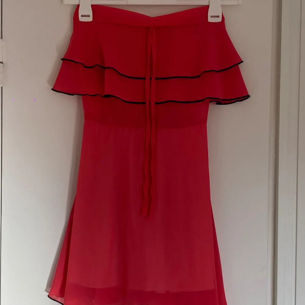 Så fin volangklänning, en kort klänning med lite svarat detaljer. Seg lite ut som att klännign är väldigt röd men är mer åt rosa och orange hållet.. Klänningar.