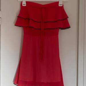 Så fin volangklänning, en kort klänning med lite svarat detaljer. Seg lite ut som att klännign är väldigt röd men är mer åt rosa och orange hållet.