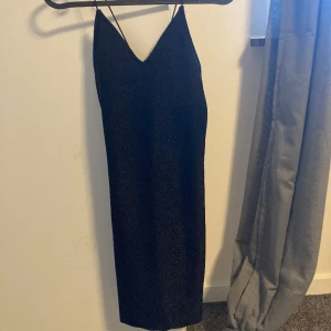Glittrig svart klänning  - En glittrig svart klänning från H&M. Jätte fin och perfekt som festklänning. Använt vid några tillfällen, säljer för den är för liten. Den är i bra skicka och väldigt bekväm! 