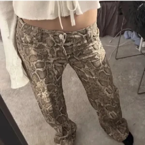 Ormmönstrade byxor/jeans - Säljer dessa helt oanvända byxor med taggen kvar då de va förstora, pris kan diskuteras🩷 helt slutsålda. Lånad bild 
