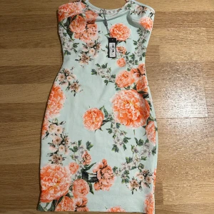 Blommig klänning - Blommig  kortare klänning från Nelly, storlek XS. Oanvänd! 