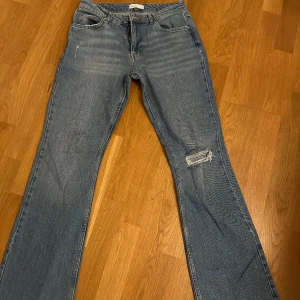 Gina Tricot full length flare jeans - Bootcut jeans med hål på ena knät i en tvättad blå färg. Använt fåtal gånger. nypris 499🩵