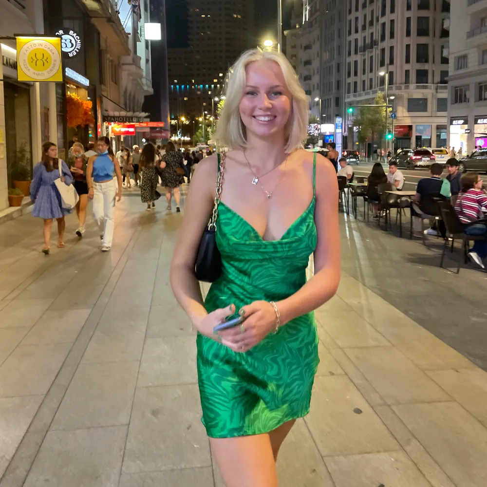 En kort grön glansig klänning från en butik i Madrid som jag ej kommer ihåg namnet på. Jag är 170 cm och ni ser ju på bilderna hur lång/kort den är på mig. Hör av er vid frågor:). Klänningar.