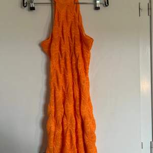 En orange glittrig klänning från Ginatricot som inte längre finns kvar. Den är tajt men stretchig och formas snyggt på kroppen. Ett glittrigt fint mönster på klänningen. Halterneck med knäppen i nacken.  I stl M, passar även S och XS. 