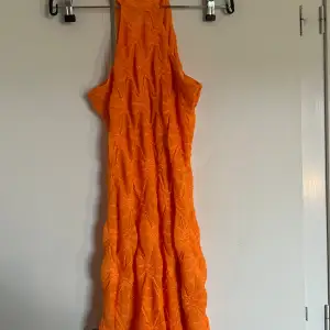 En orange glittrig klänning från Ginatricot som inte längre finns kvar. Den är tajt men stretchig och formas snyggt på kroppen. Ett glittrigt fint mönster på klänningen. Halterneck med knäppen i nacken.  I stl M, passar även S och XS. 