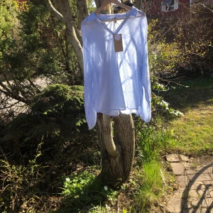 Två sommarskjortor/ sommarblusar  - En blå vit  randig och en rosa vit randig skjorta/ blus säljes. De är aldrig använda och prislappen sitter kvar. Pris per skjorta 450 kronor.
