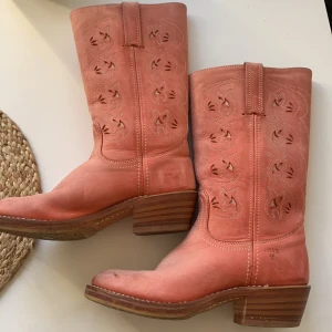 Rosa cowboy stövlar - Rosa handgjorda cowboystövlar i äkta läder. Superfint mönster och inga hål eller större slitningar, tappat färg med åren men annars sjukt bra skick. Storlek 40 passar mig som har 38 i vanliga fall. Finns på etsy för runt 3000💕