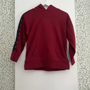 En vinröd hoodie som tyvärr inte kommer till användning längre i storlek 138/142 från champion 