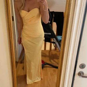 Gul balklänning - Gul balklänning i satin! Endast testad, ej använd. Är 177cm lång och denna går till marken på mig, så passar både långa och korta i längden. Superfin gul färg som syns tydligare på sista bilden. Stretchig och formar sig fint efter kroppen!