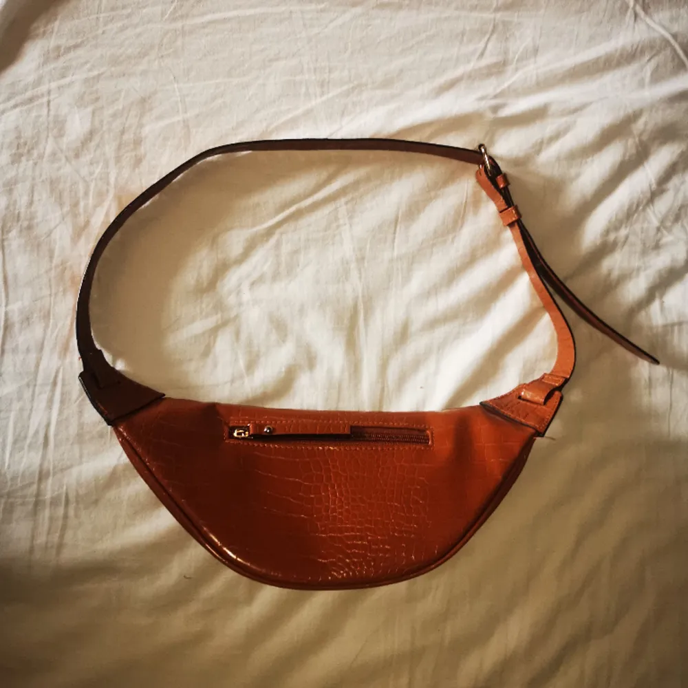 Riktigt snygg orange-brun magväska med justerbar rem och guldiga detaljer, som nyskick då den nästan aldrig varit använd. Den är krokodilmönstrad och har flera fack vilket är mycket praktiskt. Skriv för mer info💓. Väskor.