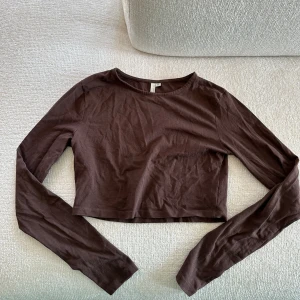 Brun långärmad magtröja - En brun långärmad magtröja från Nelly. Den brukar inte vara skrynklig utan nu har den legat i en låda under längre tid.  Super fin tröja och endast använd en gång 💕.