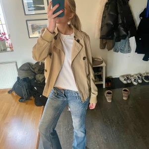 Vårjacka - Kort beige trenchcoat i storlek S köpt second hand!🩷 Den är i superbra skick utan några defekter. Säljer då den inte kommer till användning.🪩pris kan diskuteras!