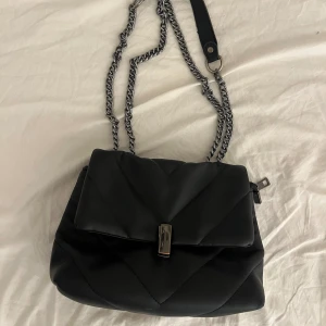 Svart väska med kedja - Bra skick, nästan aldrig använd Bredd (i bottnen) 8,5cm Höjd 14cm Längd 22,5cm