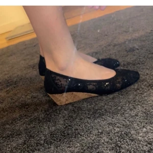 Kilklack skor - Säljer ett par snygga svarta skor med kilklack. De har en glittrig yta och en bekväm passform. Klacken är i en ljusare träfärg som ger en fin kontrast till det svarta. Perfekta för både vardag och fest!😇 (skorna har aldrig använts)