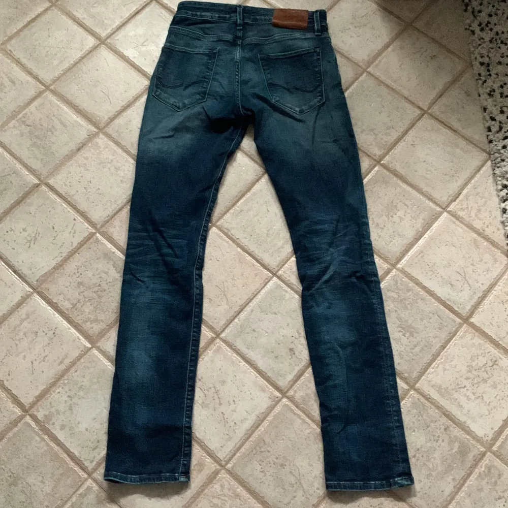 Säljer ett par snygga blå jeans från Jack & Jones. De  ä slim passform. Jeansen är i bra skick och har en cool tvättad look med lite slitningar. . Jeans & Byxor.