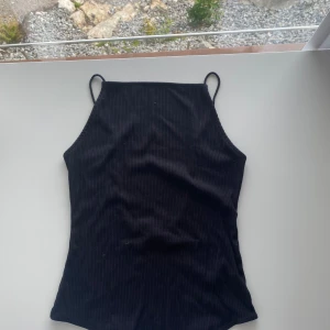 Svart ribbad body - Denna svarta ribbade bodyn från hm säljs i storlek M. Den har tunna band och en fin öppen rygg. Den är använd några gånger.