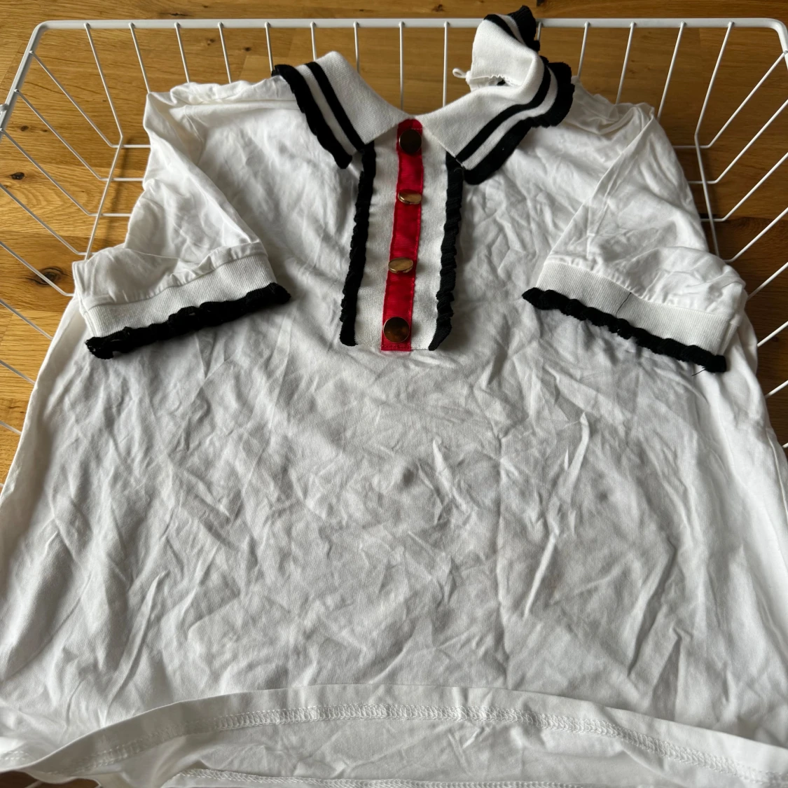 Vit blus med svarta detaljer och röda knappar