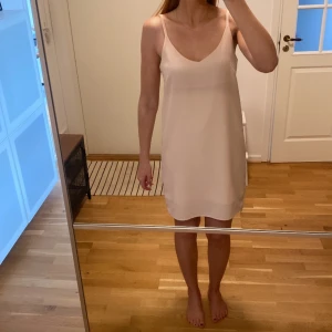 Klänning  - Ljusrosa klänning med v-ringning fram och bak. Bakre delen är också lite längre viket syns på sista bilden. 