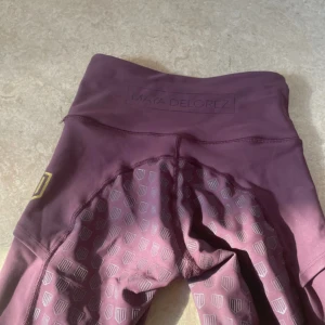 Vinröda leggings från Maya Delorez - Ett par vinröda leggings från Maya Delorez. De har hög midja och är designade i Sverige. Leggingsen har ett diskret mönster och är tillverkade i ett stretchigt material.