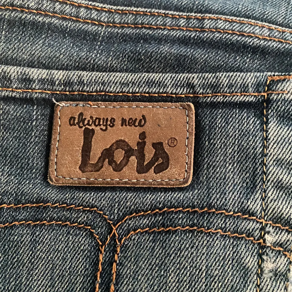 Säljer ett par mörkblå jeansshorts från Lois i storlek 34. De är lågmidjade och har en snygg, sliten look med fransiga kanter. Perfekta för sommaren! Shortsen har fem fickor och knappar samt dragkedja framtill. De är i bra skick och redo för en ny ägare.. Shorts.