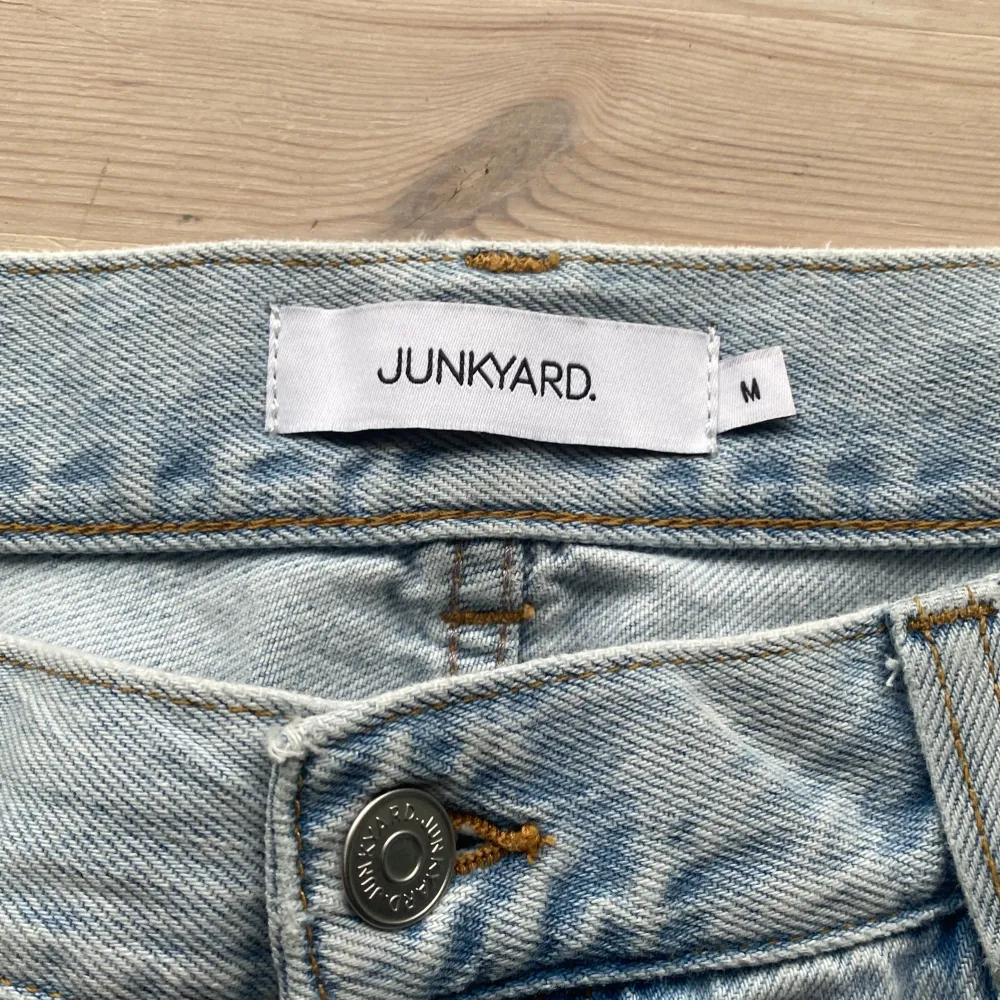 Säljer ett par ljusblå jeans från Junkyard i storlek M. De är i bra skick och har en klassisk femficksdesign med knapp och dragkedja framtill. Perfekta för en avslappnad vardagslook!. Jeans & Byxor.