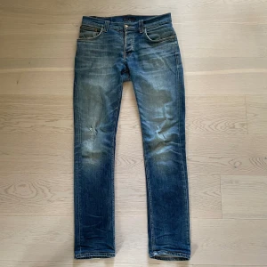 Nudie Jeans Grim tim - Snygga nudie jeans i bra skick förutom ett litet hål i höger ben, ser snyggt ut om du tycker om mer ripped. W32 L34