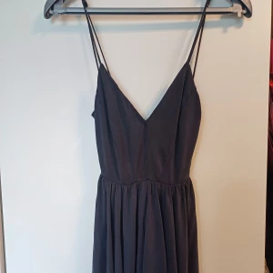 Svart klänning från Urban Outfitters - Snygg svart klänning/jumpsuit från Urban Outfitters i storlek XS. Klänningen har smala, korsande axelband och en djup v-ringning fram🖤☺️