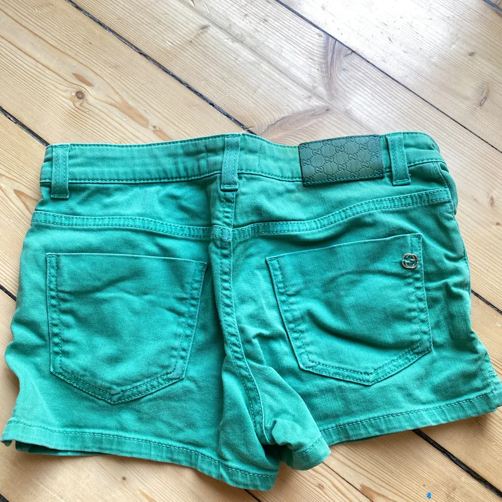 Säljer ett par snygga gröna shorts från Gucci. De är i storlek S och har en dragkedja och knapp framtill. Shortsen har två fickor fram och två bak, och är i ett mjukt och bekvämt material. Perfekta för sommaren! 🌞. Shorts.