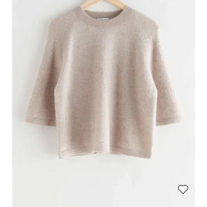 Beige stickad tröja - En mjuk och bekväm beige stickad tröja med trekvartsärm. Tröjan har en rund halsringning och en lös passform, vilket gör den perfekt för både vardag och avslappnade tillfällen.