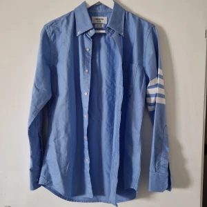 THOM BROWNE skjorta  - Bra skick Från THOM BROWNE ,New York Amerikansk storlek : 2. Passar till både S/ M. Priset : gäller budgivning  Kan mötas i city " Ålens huvudentré " 