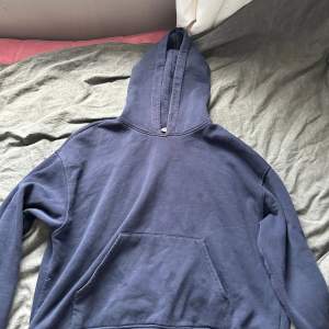 En bekväm mörkblå hoodie från Bikbok. Tröjan har en stor ficka på framsidan och en huva med dragsko. Perfekt för vardagsbruk.