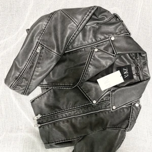 Svart skinnjacka från Zara - Säljer en snygg svart skinnjacka från Zara i storlek M. Jackan har en cool bikerstil. Perfekt för höst och vår! 🖤