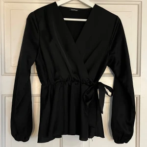 Svart omlottopp från Boohoo - Säljer en svart satin omlottopp från Boohoo i storlek S