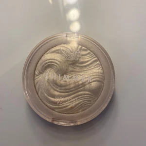Shimmer Highlighter från MUA Makeup Academy - Säljer en superfin shimmer highlighter från MUA Makeup Academy. Den har en vacker, skimrande finish som ger en fantastisk glow. Kommer i en rund förpackning med ett vågigt mönster på själva highlightern. Använd ett par gånger men fortfarande i bra skick!