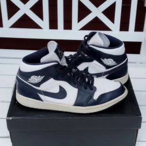 Air Jordan 1 Mid White/Metallic Size 12 Gold-Obsidian 554724-174 - Säljer ett par Air Jordan 1 Mid i färgen Navy/White. Skorna är i gott skick med några mindre tecken på användning. De kommer med originalboxen.   Strl: EUR 46  Kontakta mig gärna vid frågor!