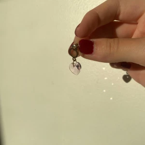 Rosa och guldiga örhängen - Guldiga örhängen med rosa gnistrande hjärtan. Köpta på en färja, därför osäker på märket. Pris kan självklart diskuteras!