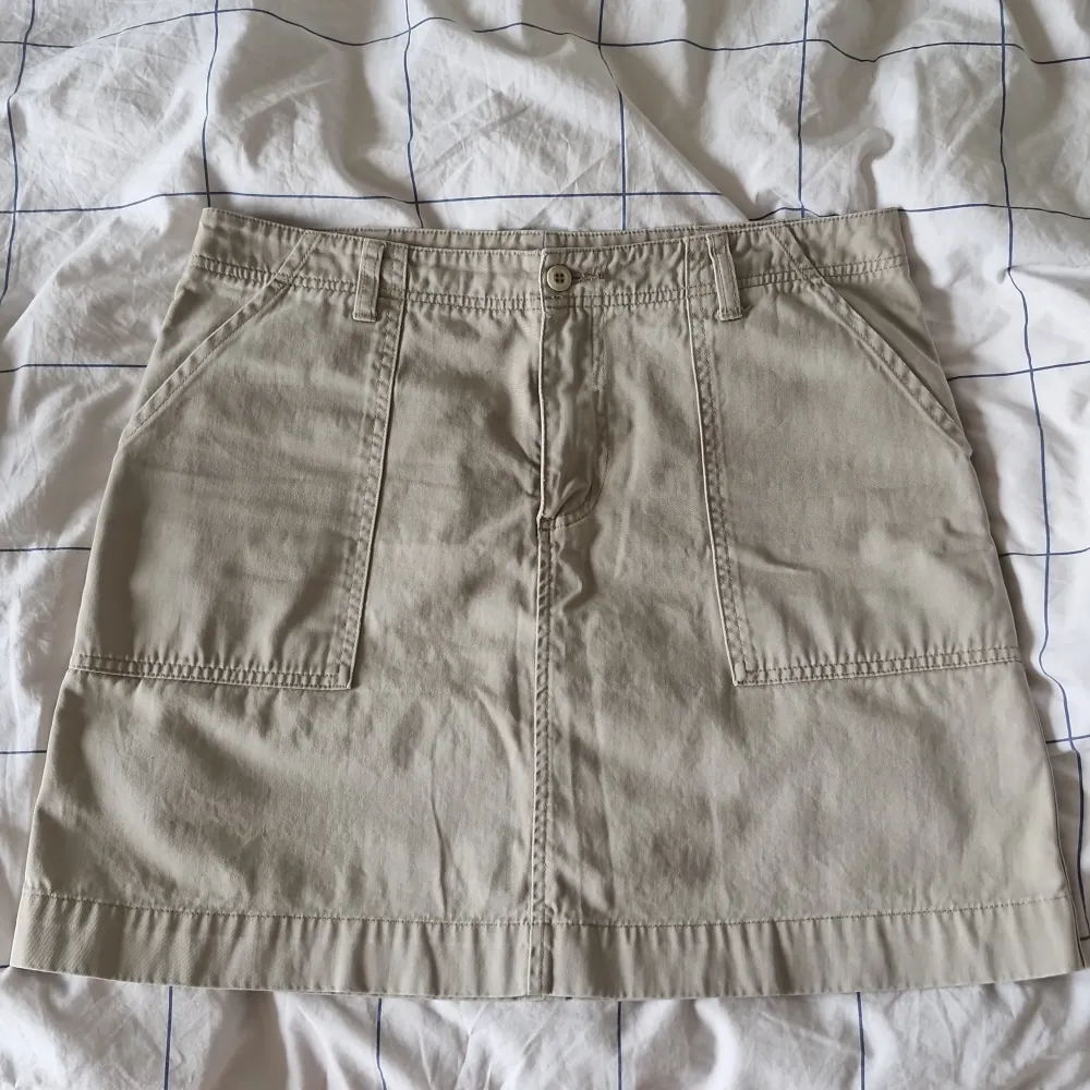 En beige kjol från M52 Pants med två framfickor och två bakfickor. Kjolen har en knapp och dragkedja framtill samt bälteshällor. Min mammas gamla kjol vet inte exakt hur gammal den är men skulle gissa runt 25-30 år. Det är en normalmidjad kjol som går ner till knäna på mig (160cm). Slriv för fler specifiserade bilder 🤗. Kjolar.