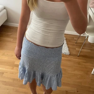 Blommig kjol - Fin blommig blå volangkjol från Laget 157. Stor i storleken och strechig! Säljer den då den inte kommer till användning💗