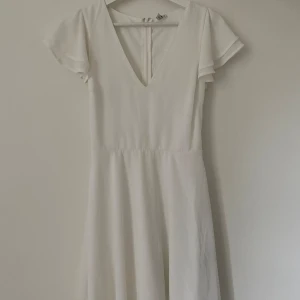 Vit klänning - Vit kort klänning från Nelly. Använd fåtal gånger, liten fläck bak på kjolen annars bra skick