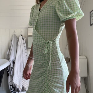 Rutig grön klänning - Bra skick alldrig andvänd. Jag har satt en säkerhetsnål vid ur ringningen för de va ganska mycket men den kan man ta bort