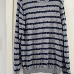 Ny grå och marinblå randig stickad tröja med rund hals i merinoull från Matinique i strl XL - Ny grå och marinblå randig stickad tröja med rund hals i merinoull från Matinique i strl XL.  Ny, aldrig använd endast tvättad en gång  Mått Över bröstet: ca 56 cm Längd från axeln och ner: ca 81 cm  100% merinoull  Kommer från ett djur och rökfritt 