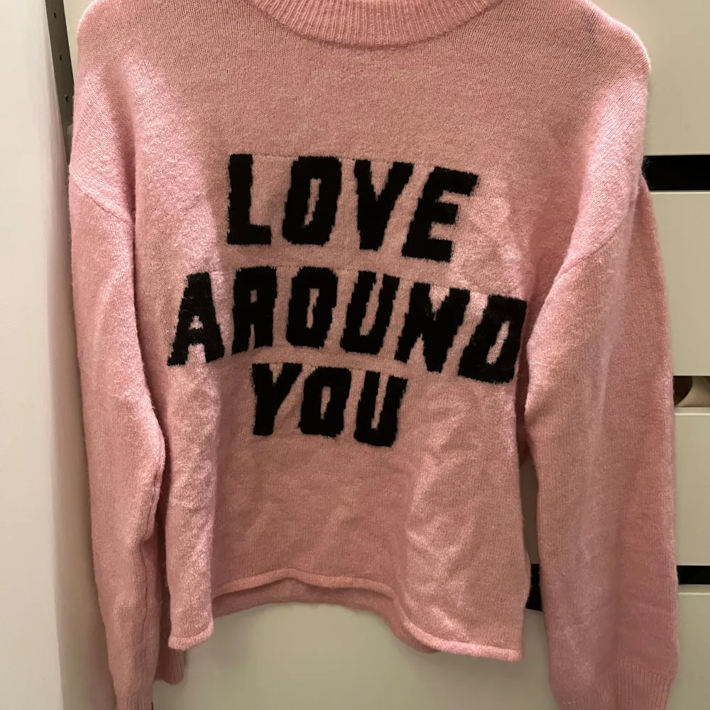 Super populär rosa stickad tröja från HM med texten love around you på. Adrig använd. Lite stor i storleken.. Tröjor & Koftor.